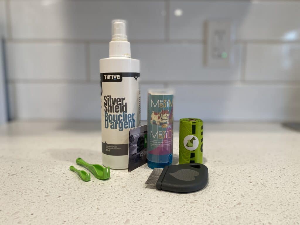 Wound spray for cats, lint roller, small tick brush, tick removing tool, and poop bags - all are placed on the counter